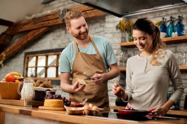 Happy man and his girlfriend making a meal in the morning in their kitchen. 