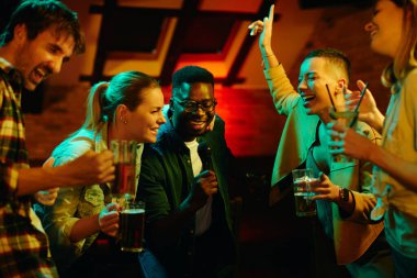 Genç mutlu yetişkinler gece bir barda eğleniyor ve karaoke yapıyor.. 