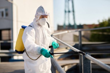 Man in protective hazmat suit disinfecting public city areas during coronavirus epidemic. 