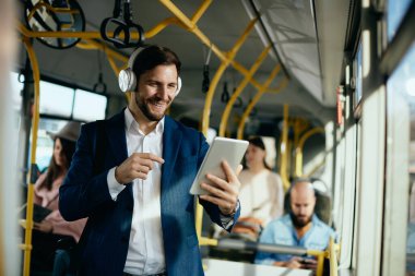 Happy businessman having video call over touchpad while traveling by public bus. 