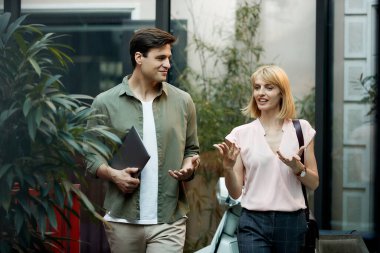 Smiling businessman communicating with his female coworker while walking on the street.