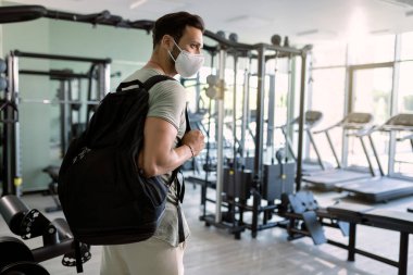Male athlete with protective mask on his face coming to sports training in health club. 