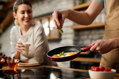 Close-up of man making fried eggs for breakfast for his girlfriend in the kitchen.