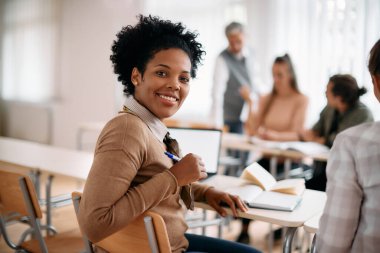 Happy African American mid adult student attending a lecture in the classroom and looking at camera.