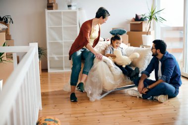 Happy family communicating while relaxing in the living room of their new home.