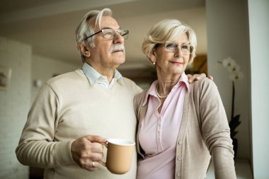 Evdeki pencerenin kenarında hayal kuran olgun çiftler günü. 