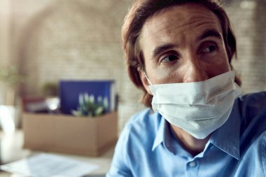 Distraught businessman wearing protective face mask and thinking after being fired at work. 