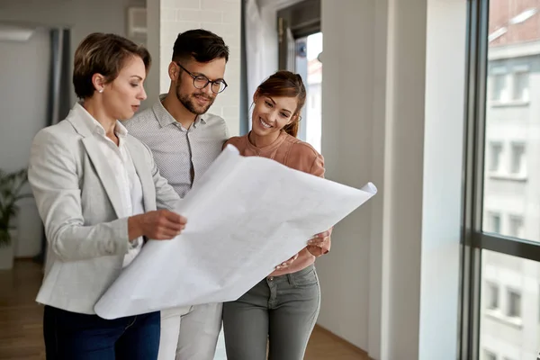 Young Couple Examining Blueprints Real Estate Agent While Buying New — ストック写真