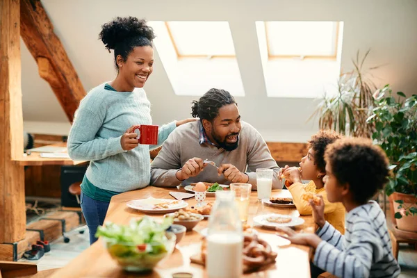 Happy African American parents talking to their kids during family breakfast at home.