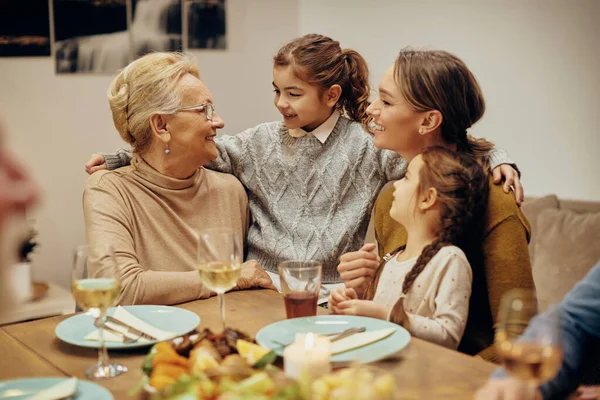 Happy female members of extended family communicating during a meal in dining room.