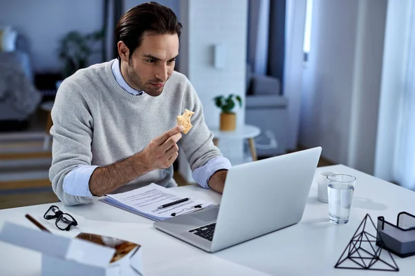 Young Freelance Worker Eating While Working Computer Home — Stockfoto
