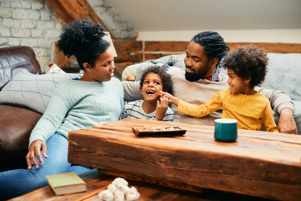 African American parents having fun with their kids at home. Little girl in pinching brother\'s cheek.