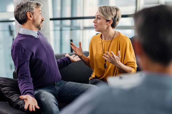 Муж и жена спорят во время встречи с психотерапевтом в офисе. 