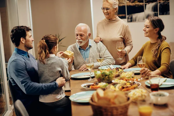 Happy Grandfather Giving Present His Granddaughter Family Lunch Dining Table — Foto Stock
