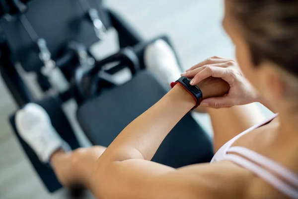 Close-up of athletic woman using smart watch while exercising at health club.