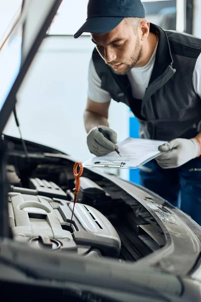 Young Mechanic Taking Notes While Engine Maintenance Car Repair Shop — Fotografia de Stock