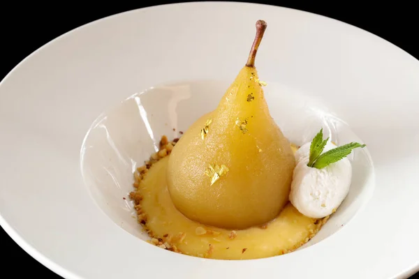 Poached pear with edible gold and vanilla ice cream.