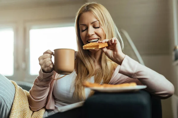 Smiling Woman Eyes Closed Eating Waffle Drinking Coffee Home — 图库照片