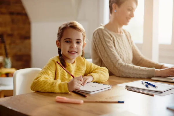 Cute Small Girl Enjoying Drawing Paper While Mother Working Computer — Foto de Stock