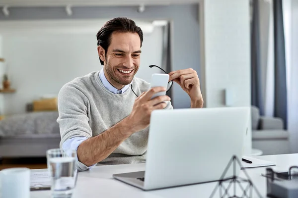 Young Happy Businessman Reading Text Message Cell Phone While Working — Stockfoto