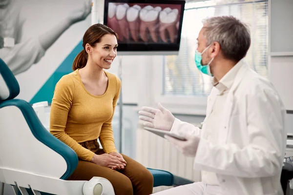 Young happy woman talking with her dentist during appointment at dental clinic. 