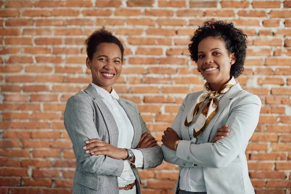 Portrait of black female business leaders standing with their arms crossed and looking at camera.