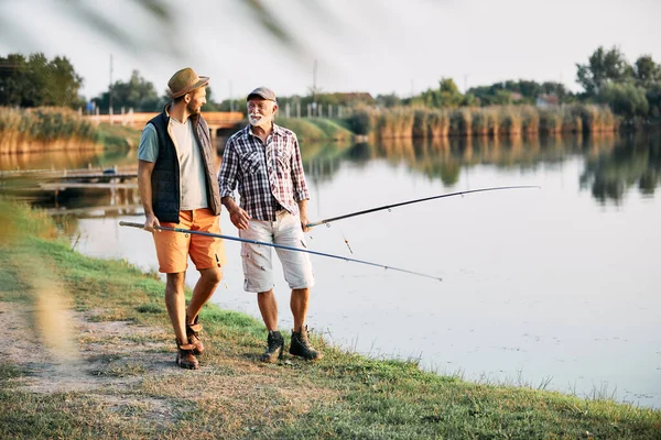 Smiling Mature Man His Adult Son Communicating While Fishing Freshwater — Stok fotoğraf