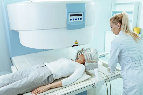 Female radiologist and mature patient during Ct head scan examination at clinic.
