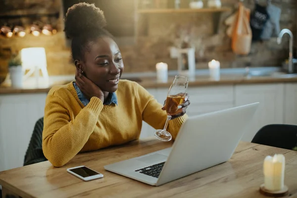 Young African American Woman Using Laptop Toasting Champagne While Talking — Fotografia de Stock