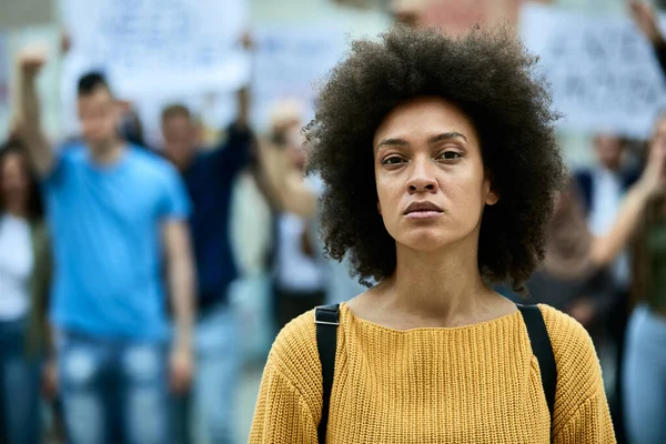 Young black woman participating in anti-racism demonstrations and looking at camera.