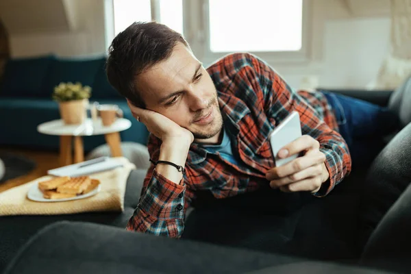 Jongeman Ontspannen Bank Het Lezen Van Sms Bericht Mobiele Telefoon — Stockfoto