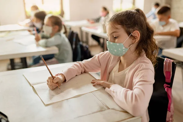 Elementary Student Writing Her Notebook While Wearing Protective Face Mask — Foto Stock