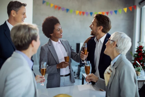 Group of happy business people having fun while drinking Champagne and celebrating in the office. Focus is on African American businesswoman.