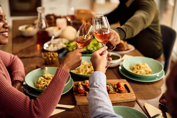 Close-up of group of friends toasting with wine glasses during a meal in dining room at home.