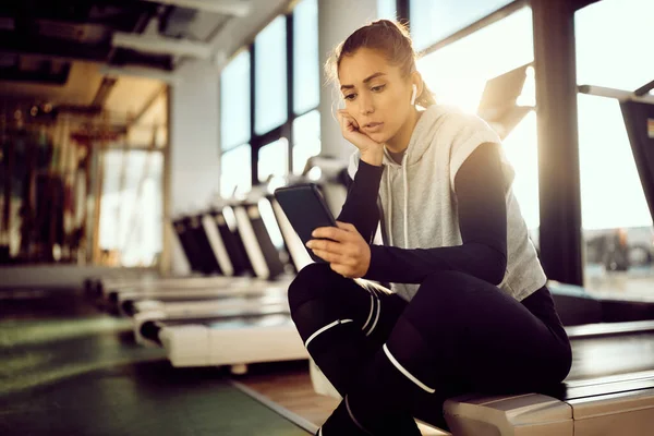 Pensive Athletic Woman Using Cell Phone Reading Text Message While — Stockfoto