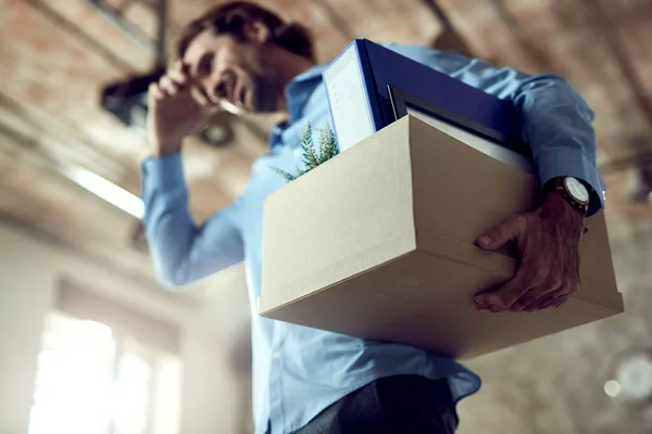 Close-up of entrepreneur carrying box with his belonging after being fired at work.