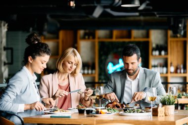Small group of coworkers having lunch together and eating in restaurant.
