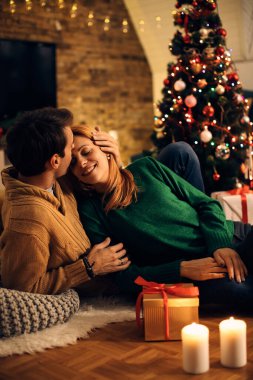 Affectionate man kissing his wife while spending Christmas eve at home. 