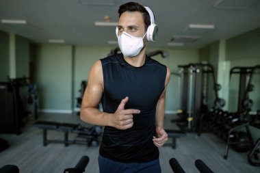 Athletic man exercising on running track and wearing protective face mask due to coronavirus epidemic. 