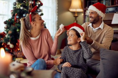Cheerful parents and their daughter having fun on Christmas day at home.