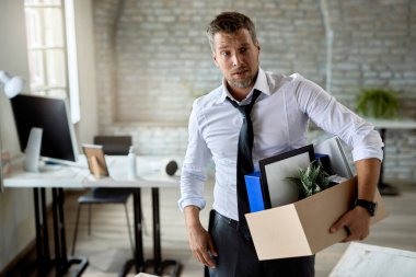 Depressed businessman carrying his belongings and leaving the office after losing his job. 