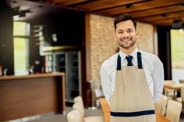 Portrait of happy happy waiter looking at camera while working in a cafe.