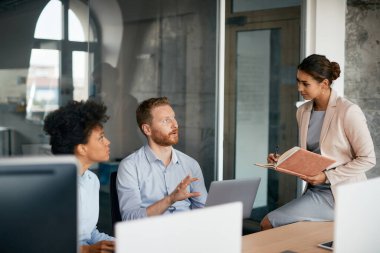 Mid adult businessman communicating with female colleagues on a meeting in the office.