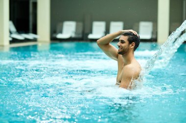Young happy man enjoying in hydrotherapy at health spa.