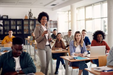 Happy African American teacher giving lecture to her students at university classroom. 