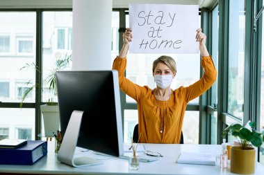 Businesswoman holding placard with stay at home text as appeal during virus epidemic. 
