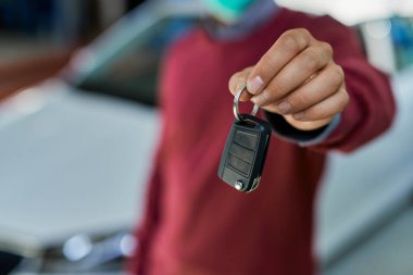 Close- up of male customer holding car key in auto repair shop. 