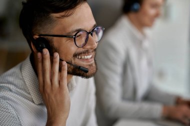 Young happy customer service agent wearing headset while working at call center. 