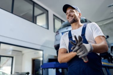Low angle view of happy repairman at car workshop. 