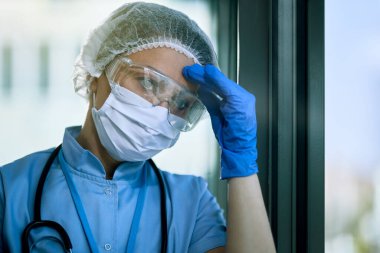 Distraught healthcare worker feeling exhausted while working at the hospital during corona virus epidemic. 